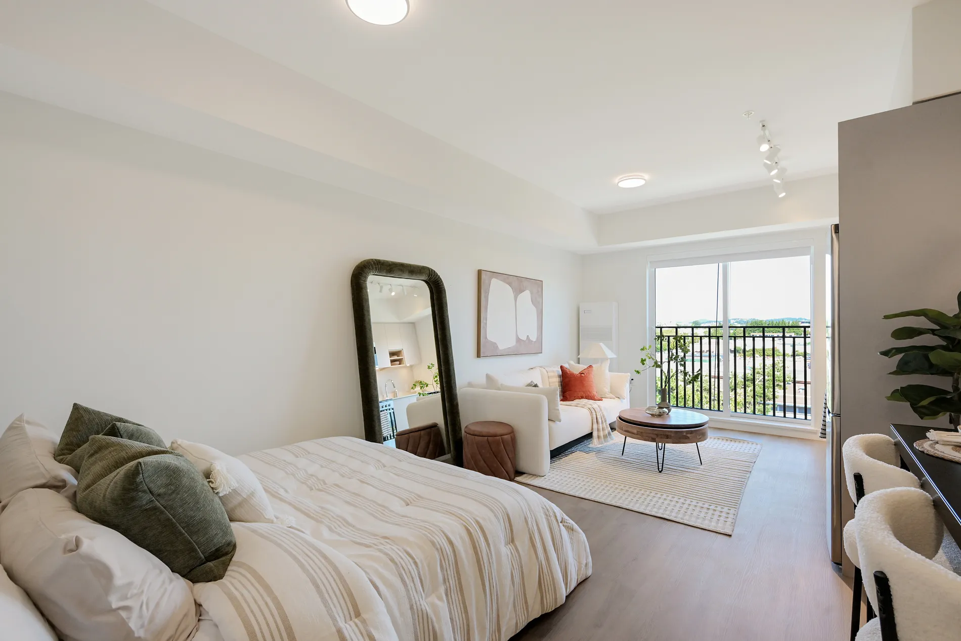 Bright living space with bed, sofa, coffee table, and balcony in this rental home at Spencer Block