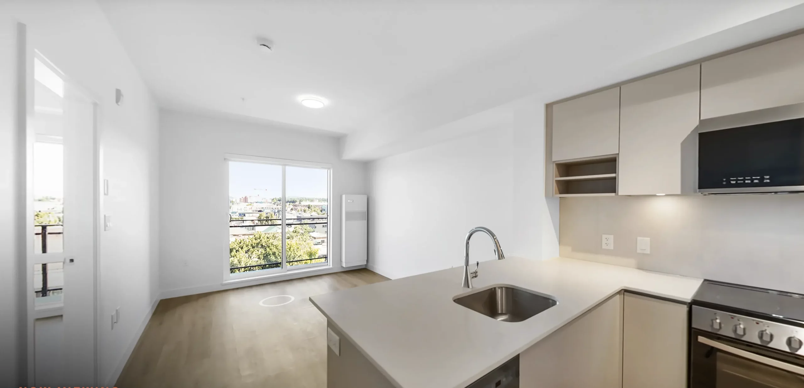 Bright kitchen with island in a Spencer Block rental home, looking out to living area and balony